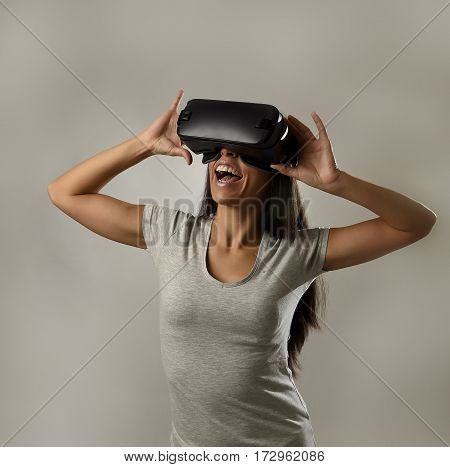 young attractive happy woman excited using 3d goggles watching 360 virtual reality vision enjoying cyber fun experience in vr simulation reality and new gaming technology isolated grey background