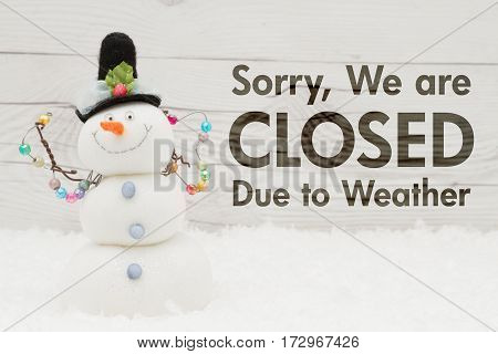 Closed due to weather message A snowman with text Closed due to weather on weathered wood