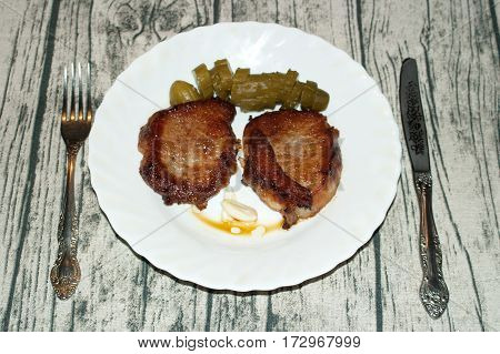 Deep fried pork steak with pickles on the plate. Table knife fork