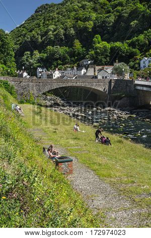 Lynmouth North Devon England 13 July 2016: People relax by the river in the village of Lynmouth.