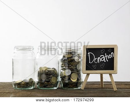 Blackboard with words donation and three saving jars from little coins ,half to full.