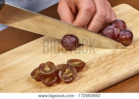 Chef-cook sliced grapes on a cutting board. Cutting ingredients closeup