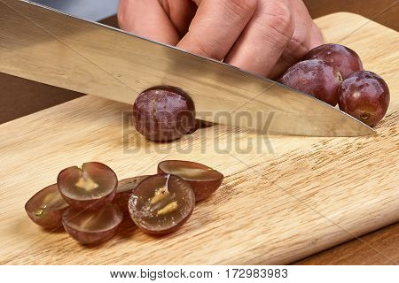 Chef-cook sliced grapes on a cutting board. Cutting ingredients closeup