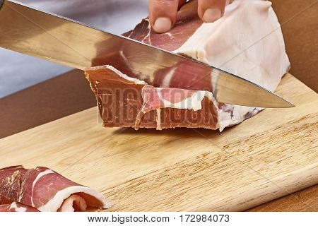 Dry cured ham thinly sliced Closeup on chef hands slices prosciutto Italian delicatessen dishes cooking process