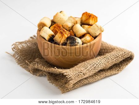Salty party snack in wooden bowl on natural jute. White background.