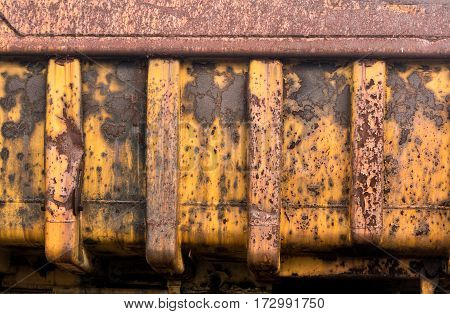 Detail of rust and remaining yellow paint on heavy yellow industrial truck and equipment abandoned in economic recession