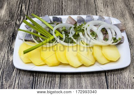 Dutch national appetizer, herring with onions.Tasty pieces of Icelandic herring with boiled potatoes and onions on the plate. National Icelandic snack Fat herring.