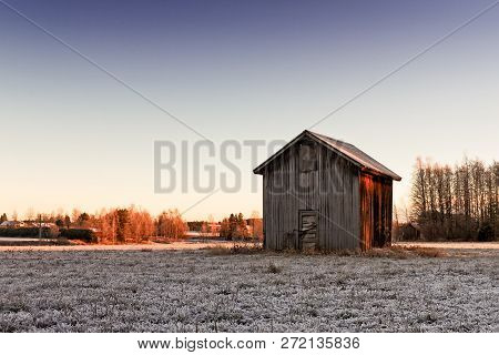 The Cold Winter Morning Sunrise Colors The Fields Beautifully At The Northern Finland. A Small Barn 