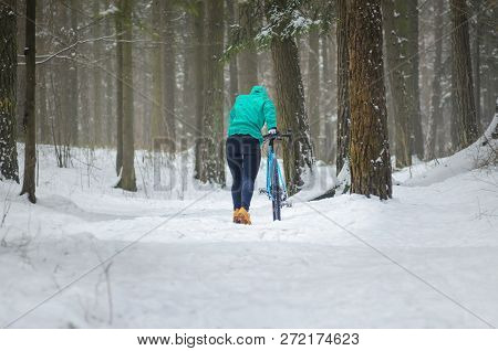 Cyclist On Cyclocross Bike Trails In The Snowy Forest In Winter. Difficult Uphill Concept. Winter Wo