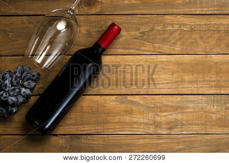 Bottle Of Wine And Glass And Grapes On Wooden Background. Top View With Copy Space.