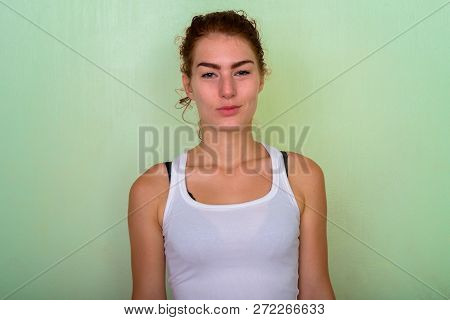 Studio Shot Of Beautiful Teenage Girl With Hair Tied Against Gre