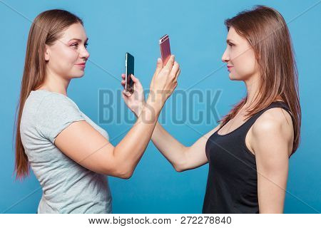 Two Caucasian Girls With Brown Hair Stand Face To Face To Each Other And Make Phone Photos Of Each O