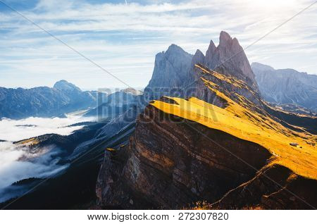 Morning view of the alpine valley in sunlight. Location place Puez-Geisler National Park, Seceda peak, Tyrol, Italy, Europe. Odle group is the landmark of Val di Funes. Discover the beauty of earth.