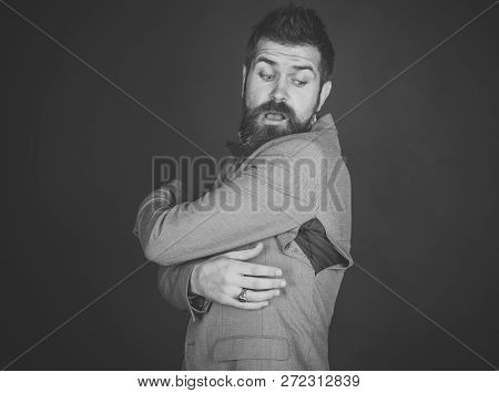 Man With Beard Wears Jacket With Hole On Dark Background. Hipster Chose Small Size Jacket, Seam Torn