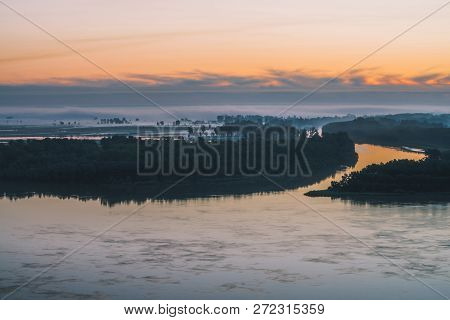 Early Blue Sky Reflected In River Water. Riverbank With Forest Under Predawn Sky. Cloudy Sunrise Sky