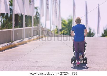 young healthy mother jogging while pushing a baby stroller at city park