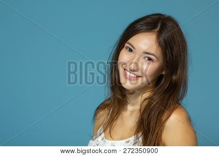 Portrait of cute morning girl. Beautiful cheerful teen girl looking at camera over blue background. Young woman posing in pajamas at studio.