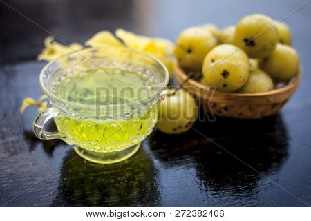 Close Up Of Ayurvedic And Organic Tea Of Amla Or Indian Gooseberry In A Transparent Cup On Wooden Su