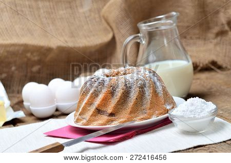 Homemade Bundt Cake Sprinkled With Sugar, Milk And Eggs In Background