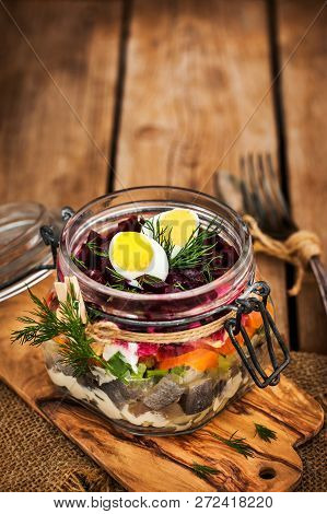 Traditional Russian Layered Betroot And Herring Salad (under A Fur Coat) In Glass Jar, Rustic Wooden