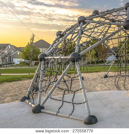 Geodesic Dome Climber Against Homes And Cloudy Sky