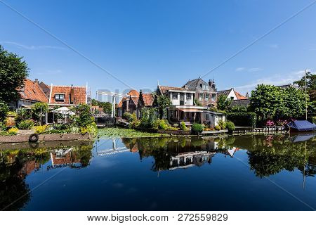 Edam's Colorful Houses Reflected In The Water, With A Nice Blue Sky
