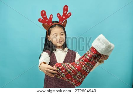 Asian Girl With A Christmas Concept Headdress Child, Close Up Of Cute Little Asian Girl On Blue Back