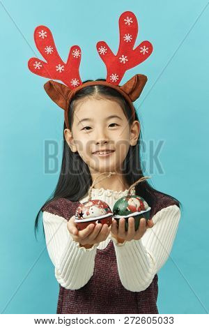 Asian Girl With A Christmas Concept Headdress Child, Close Up Of Cute Little Asian Girl On Blue Back