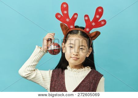 Asian Girl With A Christmas Concept Headdress Child, Close Up Of Cute Little Asian Girl On Blue Back