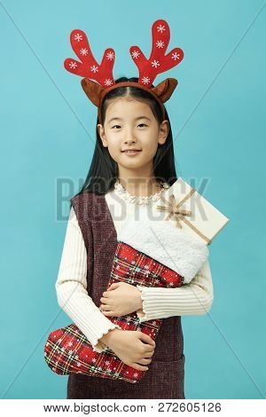 Asian Girl With A Christmas Concept Headdress Child, Close Up Of Cute Little Asian Girl On Blue Back