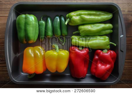 Mixed peppers on fry pan on wooden table