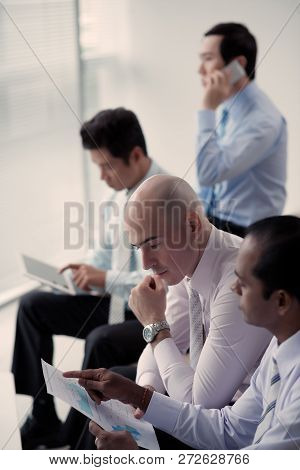 Entreprenuer Concentrated On Reading Of Financial Report Of His Indian Coworker