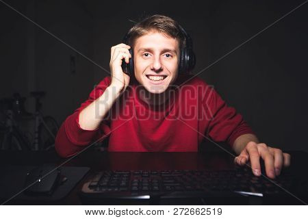 Portrait Of A Positive Gamer At Home For A Computer Game. Happy Young Man With A Headset Sitting At 