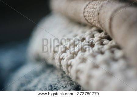 Three Woolen Sweaters Of Different Colors Lie In A Pile On A Dark Background