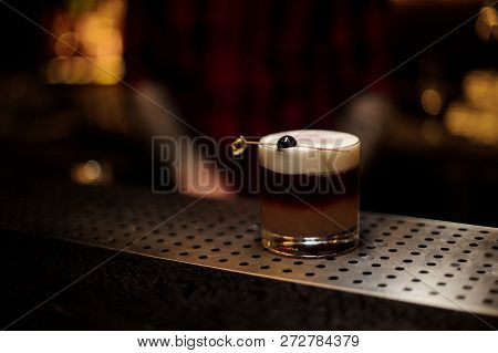Glass Of A Delicious New York Sour Cocktail Standing On The Bar Counter On The Blurred Dark Backgrou