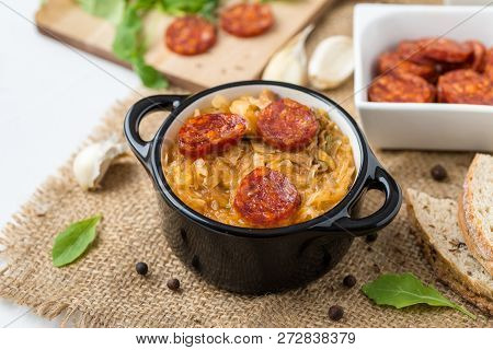 Slovak Christmas National Cabbage Soup In Two Small Black Pots With Sausage On The Tablecloth Backgr