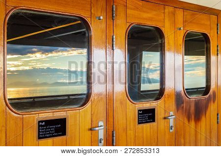 Cruise Ship Heavy Varnished Wood Exterior Doors With Windows Reflecting The Sea.