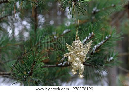 Gold angel for the Christmas. The beautiful decoration on the Christmas tree. Gold shiny Christmas angel on the fir branch. New Year gifts. The spirit of Christmas. Christmas traditions. Winter mood and love