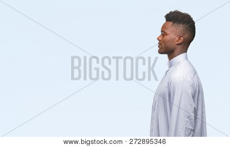 Young arabic african man wearing traditional djellaba over isolated background looking to side, relax profile pose with natural face with confident smile.