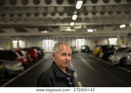 Portrait Of An Elderly Male In The Parking Garage Looking Into The Camera Smiling