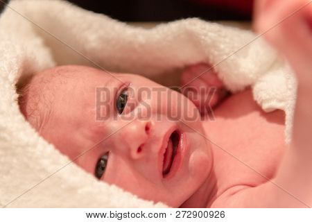 Infant In Distress Looking At The Camera, Wrapped In Soft White Blanket