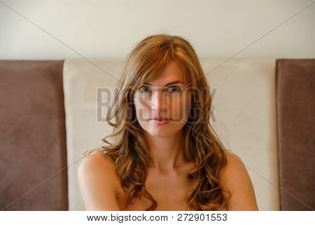 Shoulder Up Portrait Of Attractive Young Caucasian Female Against The Bed Headboard In The Bedroom