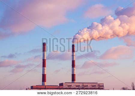 From The Factory Pipe Smoke Runs Into The Blue Sky, The Eology In The City In Ukraine At Sunset.