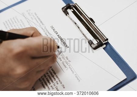 A Person Filling And Signing Dealer Agreement