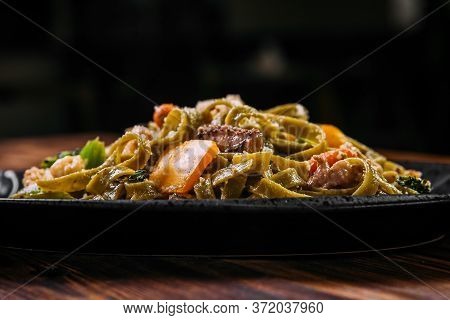 Closeup Side View On Spinach Fettuccine Pasta With Beef And Vegetables On The Wooden Table, Horizont