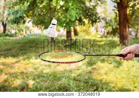 Racket With A Shuttlecock In The Air On A Background Of Greenery. Playing Badminton In The Open Air