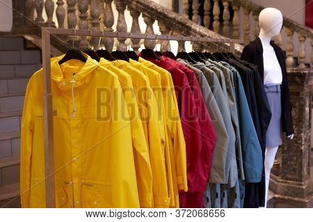 Bright Colorful Autumn Raincoats Hanging At A Fashion Store. Closeup Of Multi-colored Yellow, Red, G