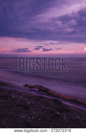 Pink Sea Sunset And Log In The Sea. Long-exposure Photos. The Water Is Like Milk.