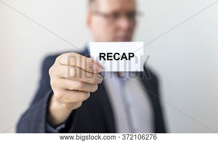 Recap Word On White Card Paper Sheet On In Hands Of A Businessman Blurred. Recap Concept.
