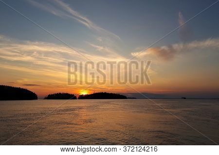 Sunset Over The Lake Behind The Islands, On The Off Of A Clear Sky. Far Off The Horizon The Ship Lea